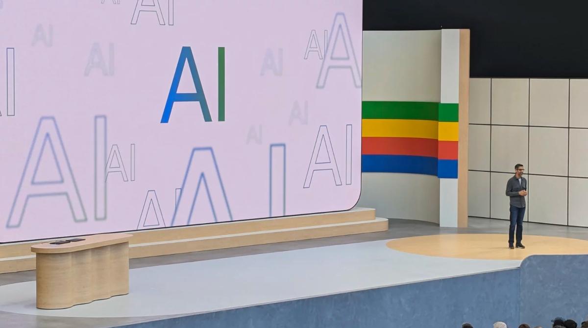 Google chief executive Sundar Pichai stands on a stage in front of a background with AI in bold lettering over it.