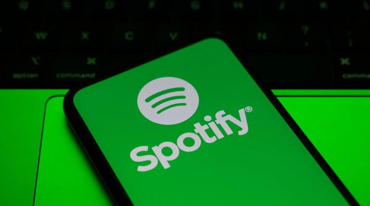 A smartphone with the spotify logo displayed on it against a green background.